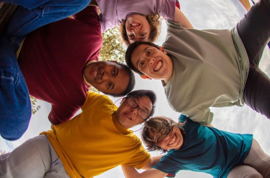 A group of children and adolescents smiling and hugging. Un grupo de niños y adolescentes sonriendo y abrazándose.